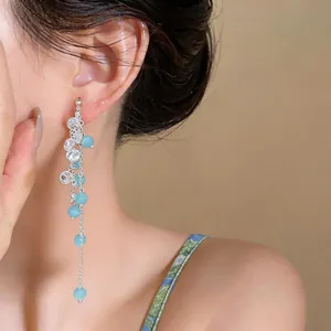 Detail view of long tassel earrings with blue cat eye stones and sparkling zircons