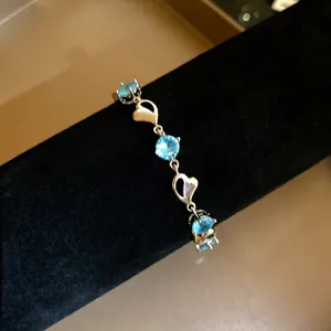 Detail view of an elegant heart bracelet with bright blue zircon stones on black velvet