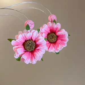 Macro view van handgemaakte roze stoffen bloem daisy oorbellen met fijne details.