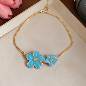 Detailed macro view of a gold chain necklace with blue enamel flower pendants