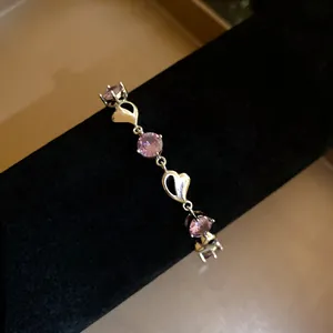 Detailed shot of a silver heart bracelet with sparkling pink round zircons on black velvet