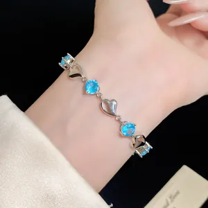 Close-up of a silver-toned heart bracelet with light blue zircons on a wrist