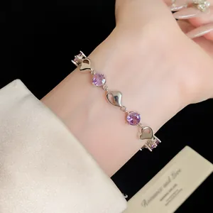 Close-up of silver heart-shaped bracelet with purple cubic zirconia on wrist