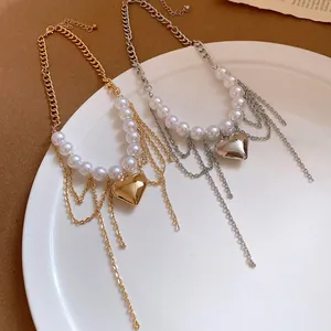 Detail view of pearl beaded chain necklaces with heart pendants in gold and silver