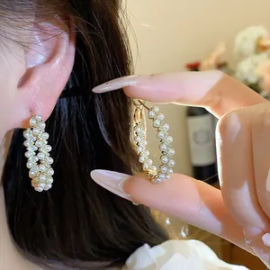 Macro detail of French style 14k gold plated pearl hoop earrings with zircon accents