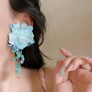 Vista dettagliata di orecchini a fiore in tessuto blu indossati per lo stile vacanza