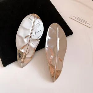 Detailed macro view of polished leaf earrings showcasing luxurious metallic surface texture