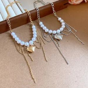 Detailed view of gold and silver heart pendant necklaces with pearls and tassels