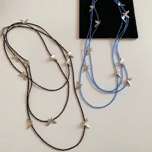 Minimalist black and blue beaded necklaces with silver butterfly charms in a layered style
