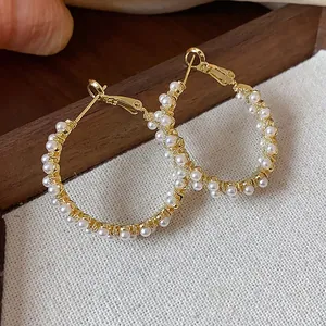Detailed view of elegant gold plated hoop earrings adorned with small white pearls