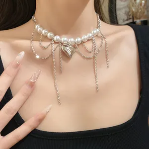 Elegant pearl necklace with silver heart pendant and draped chain detail worn by model.