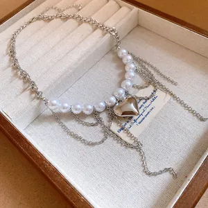 Detailed close-up of a pearl chain necklace with a silver heart pendant in a box.