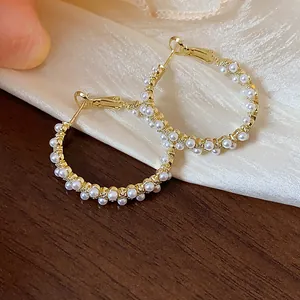 Close-up of elegant gold hoop earrings adorned with multiple small white pearls