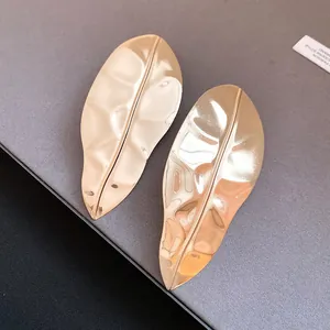 Detailed macro shot of textured gold leaf earrings with a glossy metallic finish