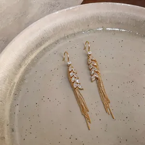 Detailed view of gold-plated wheat ear earrings with sparkling zircons and tassels.