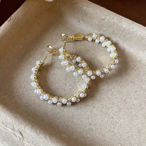 Detailed view of elegant pearl hoop earrings with 14k gold plating and textured finish