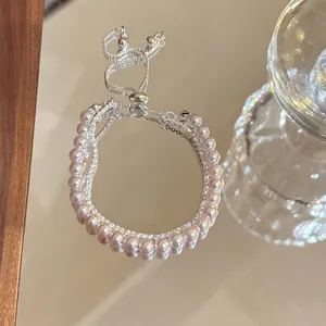 Detailed view of elegant double-layer pearl bracelet with adjustable silver drawstring chain.