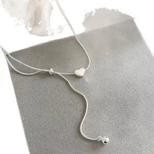 Collana a catena di serpente argento minimalista con cuore bianco e ciondolo a sfera.