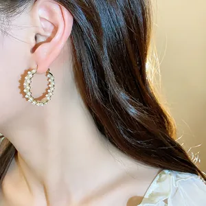 Detailed side view of a model wearing elegant 14k gold plated hoop earrings with pearls