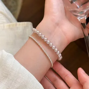 Elegant pearl and slim sparkling tennis bracelet set worn on wrist for a refined look