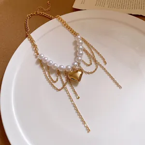 Detail view of a retro gold chain necklace with pearls and a heart-shaped pendant.