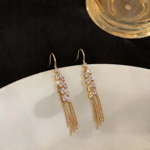Macro view of gold plated wheat earrings with sparkling zirconia and long tassels