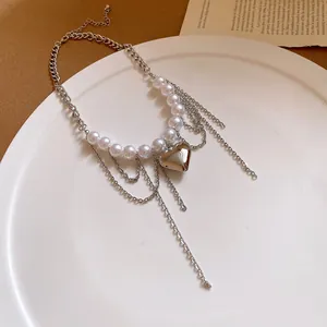 Detailed view of white pearls and a silver heart pendant on a multi-layered chain
