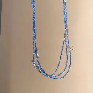 Detail view of multi-layered blue beaded necklace with elegant silver butterfly charms.