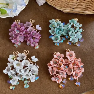 Detailed view of handmade fabric flower earrings with iridescent crystal heart tassels.