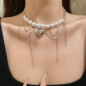 Macro view of a retro pearl beaded chain necklace with a silver heart pendant on a model.