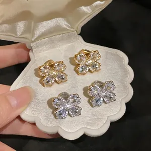 Elegant 18K gold plated zircon flower shaped ear clips displayed in a white shell box
