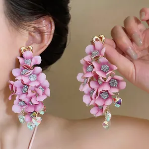 Detailed close-up of pink fabric flower drop earrings with crystal heart tassels