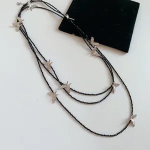Close-up of a three-layered black beaded necklace featuring delicate silver butterfly charms.