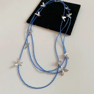 Detailed macro view of multi-layered blue beaded necklace featuring elegant silver bird charms