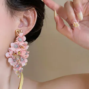 Close-up of elegant pink fabric flower tassel earrings with gold heart stud on model