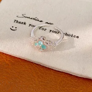 Eleganter verstellbarer Silberring mit grünem Zirkon-Kleeblatt auf weißem Beutel