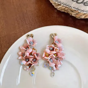 Detailed macro shot of pink fabric flower earrings with heart studs and crystal tassels