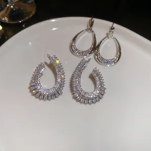 Elegant silver-toned teardrop earrings encrusted with sparkling zircons on a white plate