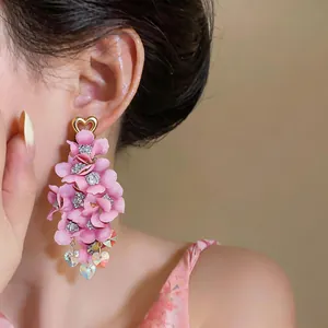 Close-up of elegant pink fabric flower tassel earrings worn by a model