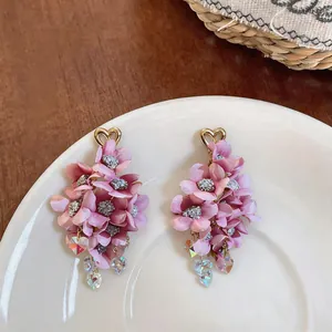 Macro detail of pink fabric flower tassel earrings with gold heart studs and crystals