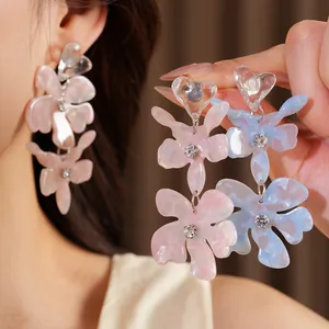 Macro view of elegant pastel resin flower earrings featuring heart studs and crystals