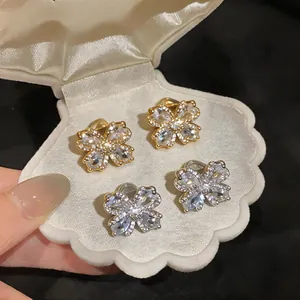 Detail of elegant 18K gold plated flower ear clips with sparkling cubic zirconia petals