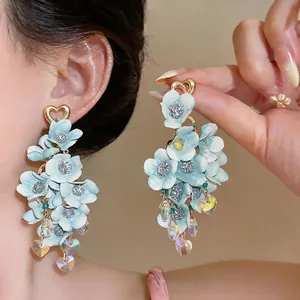 Close-up of elegant light blue fabric flower dangle earrings with iridescent heart crystals
