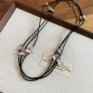 Close-up detail of a layered necklace featuring black beads and silver butterfly charms