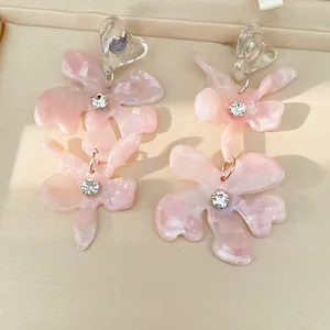 Detailed view of pink resin flower earrings with rhinestones and clear heart top in a box.