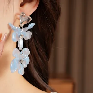 Detail of elegant blue resin flower tassel earrings with clear heart stud and crystal