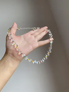 Close-up detail of transparent heart-shaped beaded necklace with colorful rainbow spacers.