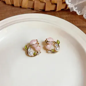 Vue rapprochée d'élégantes boucles d'oreilles tulipes roses avec perles sur assiette céramique