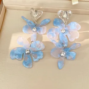 Macro view of delicate blue and pink resin flower earrings with heart studs and rhinestones