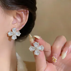 Close-up detail of 18K gold-plated zircon flower ear clips with an elegant French style
